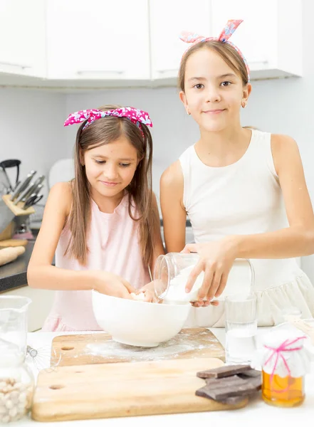 Two sisters making dough on kitchen in big white bowl — Stock Photo, Image