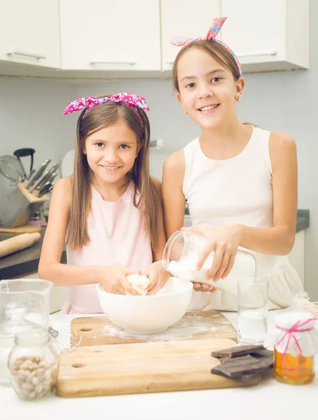 Portrait of two sister mixing ingredients for dough in big bowl — Stock Photo, Image