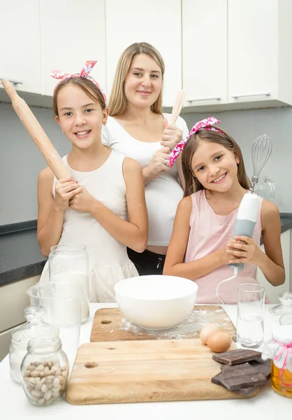 Felice giovane madre e due figlie in posa con utensile da cucina — Foto Stock