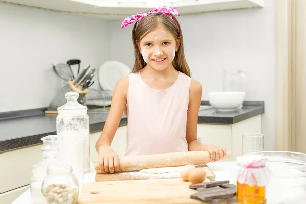 Sorridente ragazza rotolamento pasta sulla cucina disordinato — Foto Stock