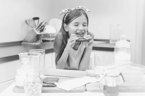 Schwarz-Weiß-Porträt eines süßen Mädchens, das sich auf einen Küchentisch lehnt — Stockfoto