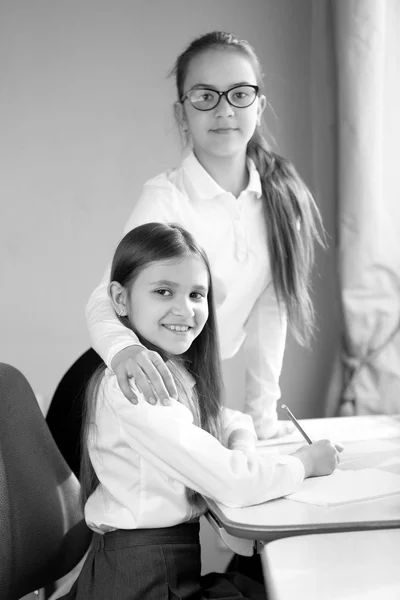 Black and white portrait of two happy schoolgirls doing homework — Stock Photo, Image