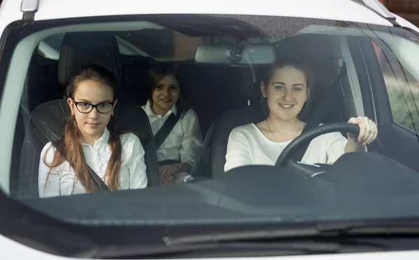 Madre y dos hijas en uniforme escolar cabalgando en coche — Foto de Stock