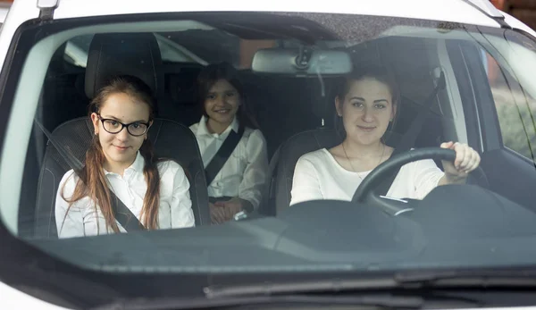 Portrait through windscreen of happy smiling mother and two daug — Stock Photo, Image