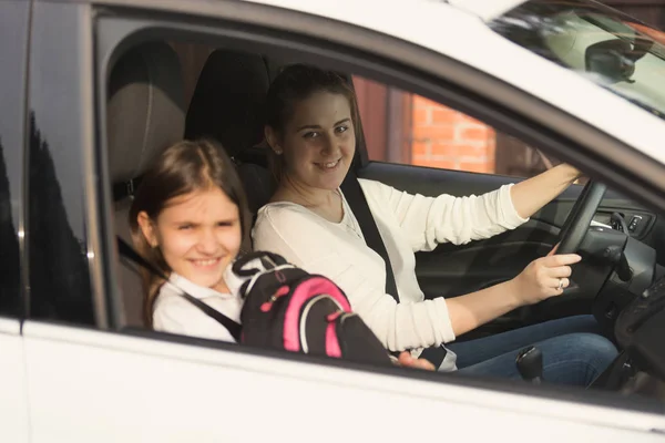 Beautiful mother driving car with daughter to school — Stock Photo, Image