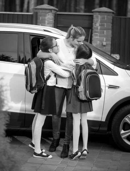 Black and white image of happy mother kissing her two daughters — Stock Photo, Image
