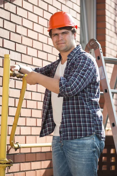 Fontanero joven en hardhat mantener tuberías de gas amarillo fuera de — Foto de Stock