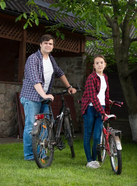 Hombre joven y adolescente posando con bicicletas en la hierba en el parque — Foto de Stock