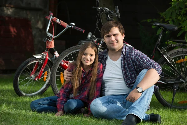 Smiling young man and cute girl relaxing on grass at park after — Stock Photo, Image