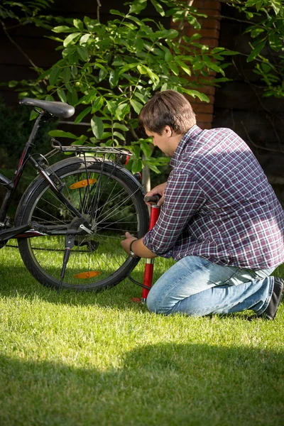 Молодой человек накачивает велосипедные задние шины — стоковое фото