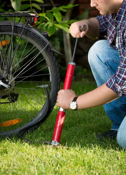 Joven bombeando neumáticos de bicicleta en el parque —  Fotos de Stock