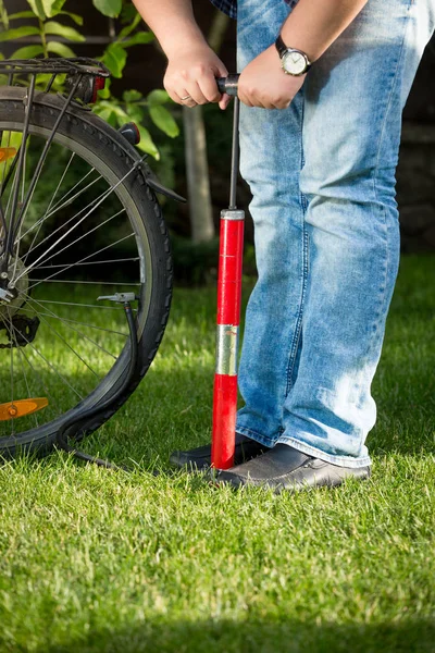 Junger Mann pumpt Fahrradrad auf Gras — Stockfoto