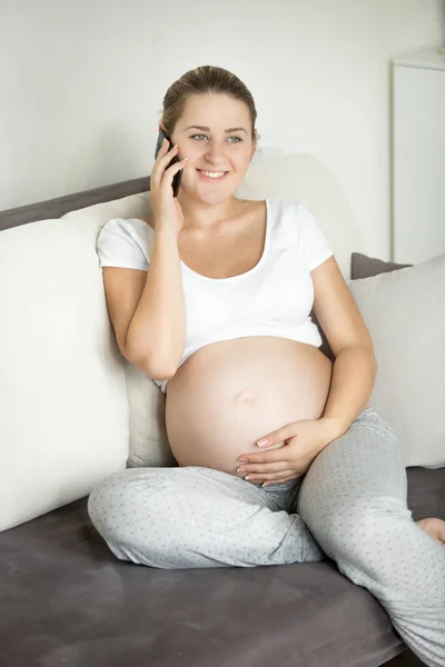 Beautiful smiling pregnant woman talking by phone on the sofa Stock Photo