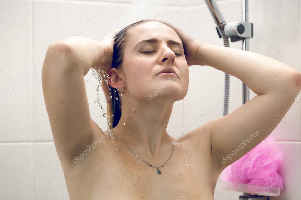 Young woman washing long hair in shower