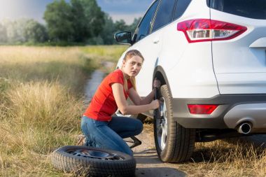 Araba tekerlek toprak yol üzerinde değişen genç kadın üzgün