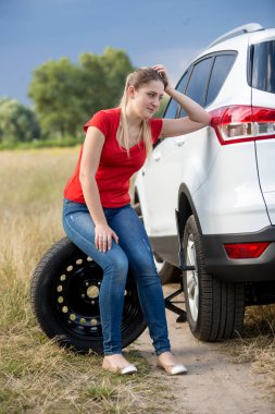 Lastik üzerinde oturan ve kırsal Road arabaya eğilerek üzgün kadın
