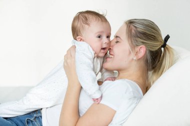 Mutlu genç anne yatakta yatarken ve onun 3 ay tutarak eski bab