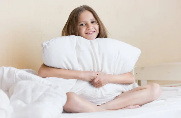 Portret piękna brunetka dziewczyna siedzi na łóżku z biały pi — Zdjęcie stockowe