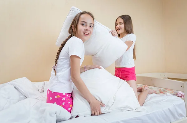 Dos hermanas teniendo pelea de almohadas en la cama — Foto de Stock