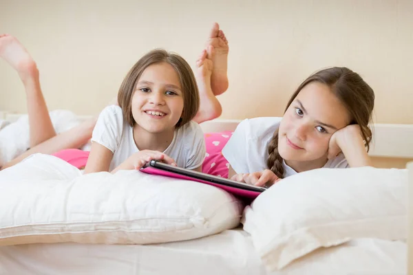 Portrait de deux adolescentes couchées au lit avec tablette numérique — Photo