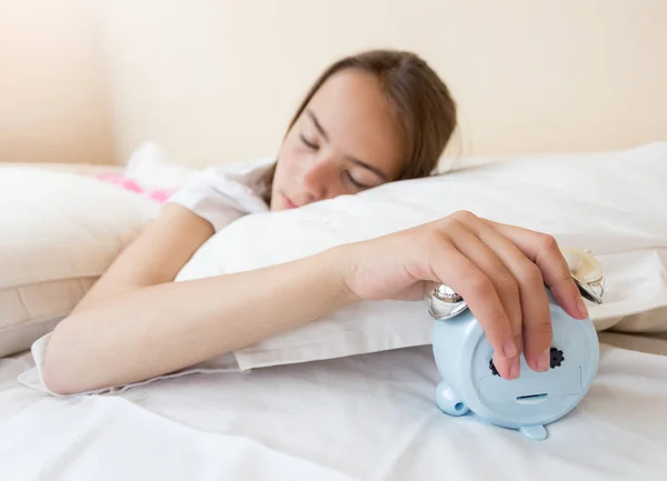 Tonårig flicka sätta ringande väckarklocka under kudden — Stockfoto