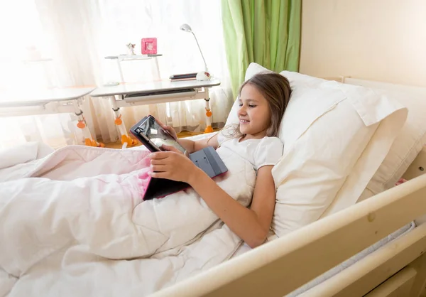 Adolescente deitada na cama de manhã e usando tablet digital — Fotografia de Stock