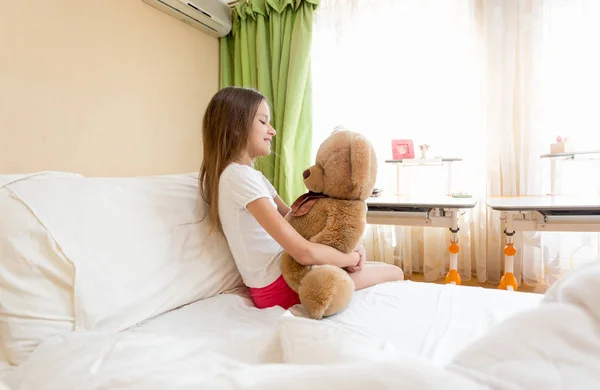Schattig meisje zit haar teddy bear knuffelen — Stockfoto