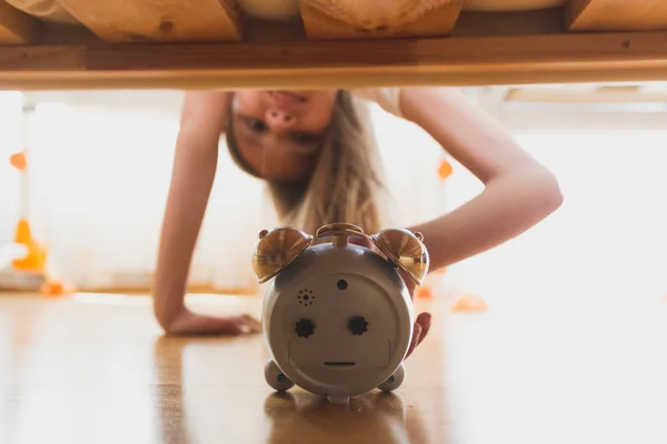 Ragazza carina che raggiunge per la sveglia sotto il letto — Foto Stock