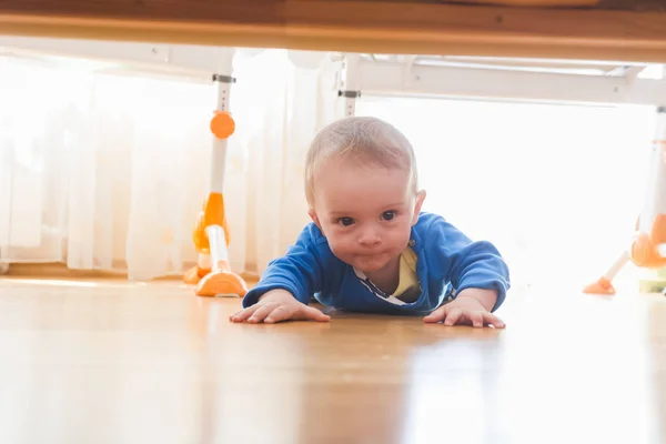 Söt baby pojke kryper och titta under sängen — Stockfoto