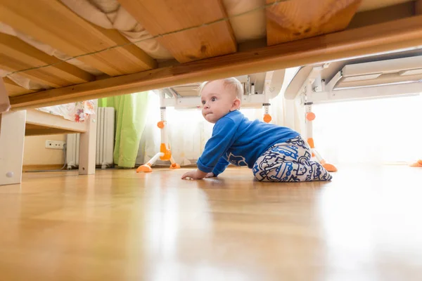 Chlapeček procházení na podlaze a při pohledu pod postelí — Stock fotografie