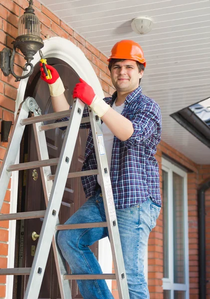 Elektricien permanent op trapladder en herstellen van buiten lamp — Stockfoto