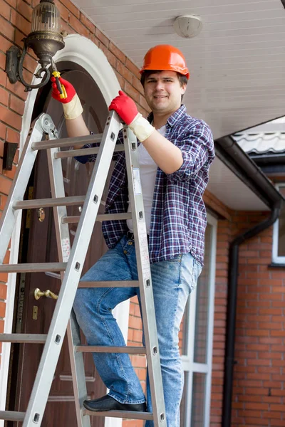 Jeune électricien en casque dur grimpant l'escabeau — Photo