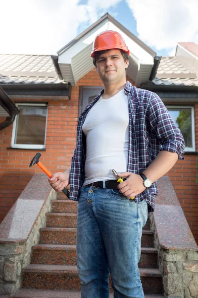 Trabajador sonriente posando frente a casa con escalera de piedra — Foto de Stock