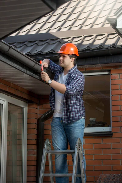 Lachende bouwvakker op stap ladder onder het dak van het huis — Stockfoto