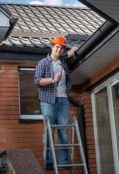Glimlachend timmerman poseren met de hamer op stap ladder onder de ro — Stockfoto