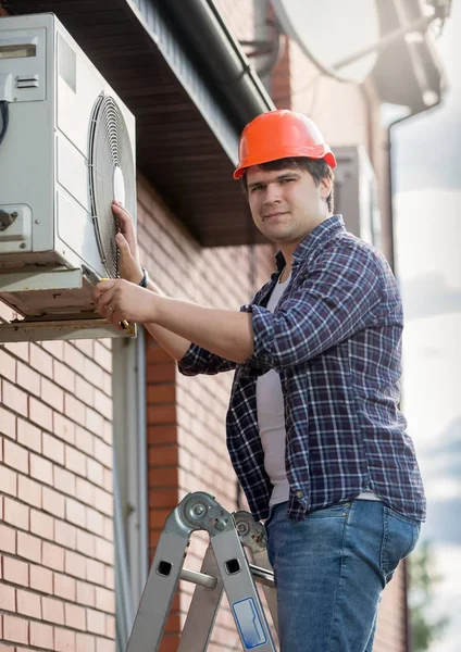 Ung ingenjör installera luftkonditioneringen på bygga yttervägg — Stockfoto