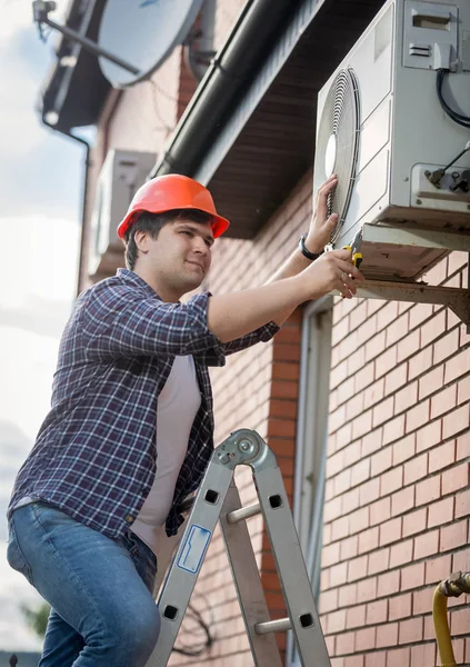 Mannelijke technicus buiten airconditioningsysteem herstellen — Stockfoto