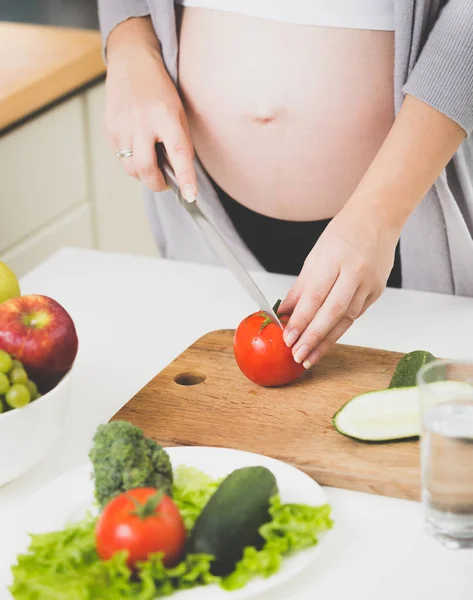 Zbliżenie obrazu Kobieta w ciąży cięcia świeżych pomidorów na sałatkę — Zdjęcie stockowe