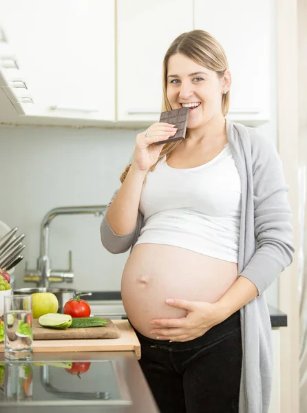 Retrato de mulher grávida sorridente posando com barra de chocolate — Fotografia de Stock