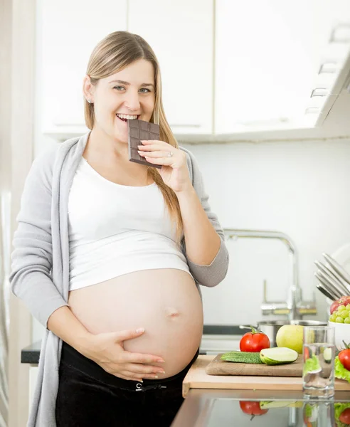 Porträtt av unga leende gravid kvinna äta choklad — Stockfoto