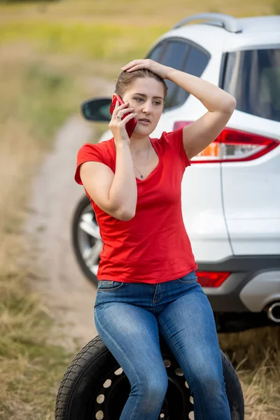 Retrato de jovem motorista sentado próximo carro quebrado e conversa — Fotografia de Stock