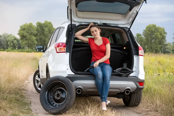 Frustrierte Frau sitzt in kaputtem Auto auf Feld — Stockfoto