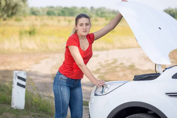 Mujer abriendo la capucha del coche roto en la carretera — Foto de Stock