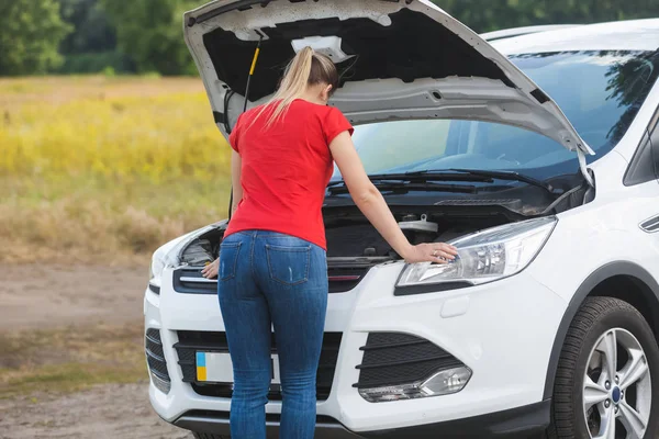 Young woman standing at broken car with open hood — Stock Photo, Image