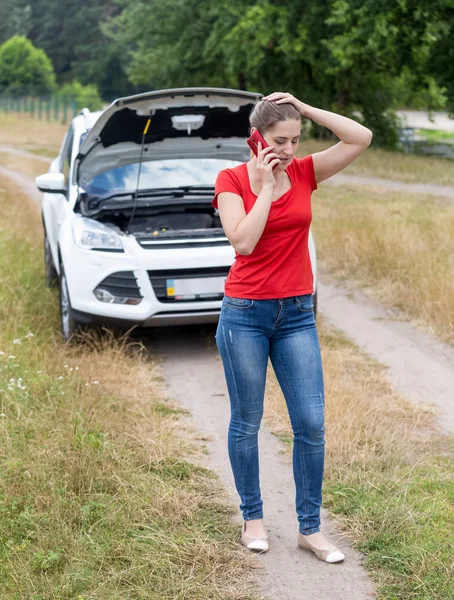Разочарованная женщина зовет на помощь свою сломанную машину в сельской местности — стоковое фото