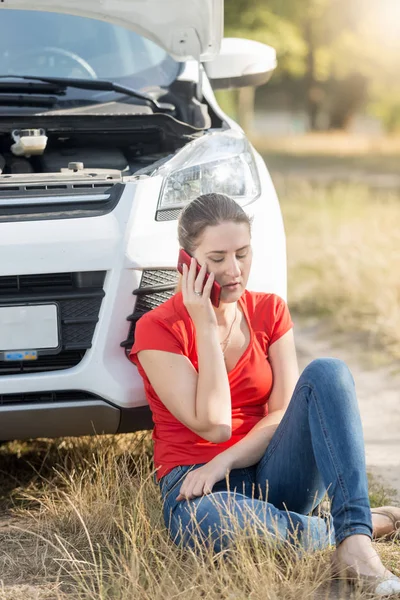 Mujer sentada en el coche roto y hablando por teléfono — Foto de Stock