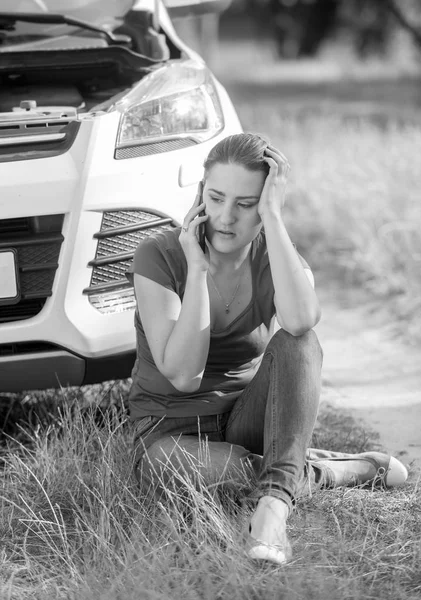 Black and white image of young woman sitting on ground and leani — Stock Photo, Image