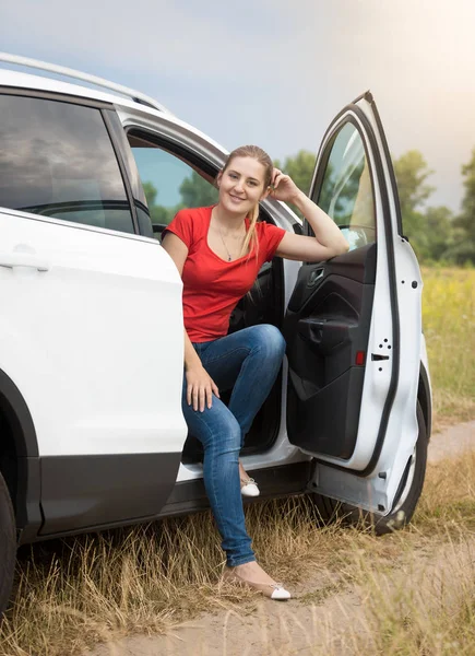 Smiling woman sitting in car at the field — Stock Photo, Image