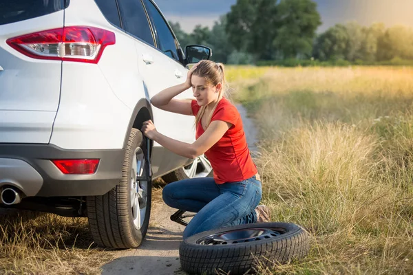 Mulher triste ficou confuso sobre a mudança de pneu furado no campo — Fotografia de Stock
