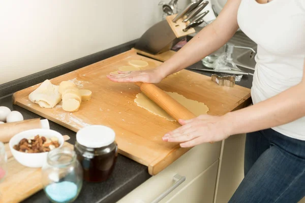 Closeup of young woman rolling dough on wooden board with pin — Stock Photo, Image